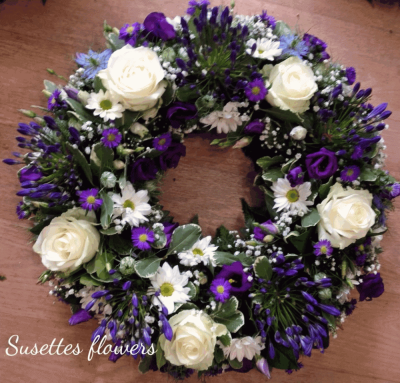 Blue & White Wreath - Blue & White Wreath
A beautiful Blue & White Wreath. Roses, Chrysanthemums, Statice , eustomia and purple Brodiea, sit perfectly alongside variegated lime Dracaena, Green pittosporum, Cocculus, Salal and Blue Thistle.

Hand delivered by your local florist in Bury St Edmunds by Susettes Flowers.

Image shown is Deuluxe.

Also avaiable in Standard & Luxury Sizes.

 

Please note that due to the seasonal availability of flowers it may be necessary to vary individual stems from those shown. Our skilled florists may substitute flowers for one similar in style, quality and value. Where our designs include a sundry item like a vase or basket it may not always be possible to include the exact item as displayed. If such an occasion arises we will make every effort to replace the item with a suitable alternative.