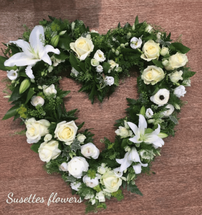 Cream & White Open Heart - An cream and white open heart. Using Cream rose, White Lily, eustomia and seasonal blooms, this is a simple and compelling tribute.

Image Shown is Luxury

Please note this item is only suitable for delivery to a funeral. Please make a selection from an alternative range, if you would like to express your sympathy to the bereaved. Product photography is indicative of the highest price point. Please note that seasonal availability of individual stems may vary from those in the picture. Our professional florist may substitute flowers for a suitable alternative, similar in style, colour, quality and value. Where flower designs include a sundry item such as a vase or basket it may not always be possible for our florists to include the exact item pictured. Every effort will be taken to ensure that the item is substituted for a similar design.Price above includes delivery charge but excludes relay fee