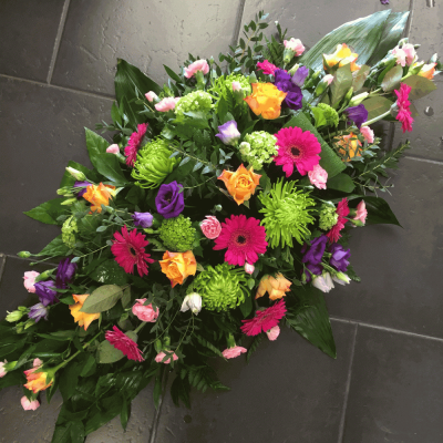 Vibrant Double Ended Spray - A vibrant double ended spray featuring orange Roses, pink Germini, purple Lisianthus with green Chrysanthemums and Carnations.

Standard 2 ft, Deluxe 2.5 ft, Luxury 3ft

Please note this item is only suitable for delivery to a funeral. Please make a selection from an alternative range, if you would like to express your sympathy to the bereaved. Product photography is indicative of the highest price point. Please note that seasonal availability of individual stems may vary from those in the picture. Our professional florist may substitute flowers for a suitable alternative, similar in style, colour, quality and value. Where flower designs include a sundry item such as a vase or basket it may not always be possible for our florists to include the exact item pictured. Every effort will be taken to ensure that the item is substituted for a similar design.Price above includes delivery charge but excludes relay fee.