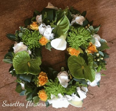 Exotic Wreath - An green and white Wreath with a spalsh of lemon. A green Anthrium, White Calla and rose wreath with a spray of lemon Roses, white calla lily and lime Hypericum neatly finished with a bloom xant and a touch of eustomia.

Image Shown Luxury 14"

Also available in Standard 10" and Deluxe 12"

Please note this item is only suitable for delivery to a funeral. Please make a selection from an alternative range, if you would like to express your sympathy to the bereaved. Product photography is indicative of the highest price point. Please note that seasonal availability of individual stems may vary from those in the picture. Our professional florist may substitute flowers for a suitable alternative, similar in style, colour, quality and value. Where flower designs include a sundry item such as a vase or basket it may not always be possible for our florists to include the exact item pictured. Every effort will be taken to ensure that the item is substituted for a similar design.Price above includes delivery charge but excludes relay fee.