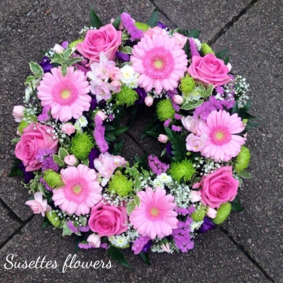 Pink Rose & Germini Wreath - An pink and lilac Wreath. A pink germini and rose wreath with a spray of pink Roses, pink germini and lime Hypericum neatly finished with a lilac xant and a touch of pink statice.

Image Shown 16"

Also available in Standard 12" and Medium 14"