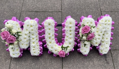 MUM Tribute - Beautiful white Chrysanthemums with a flourish of pink Roses and edged with Pink ribbon pleats, form the name MUM.

Stand included.

Please note this tribute is availble in several colour choices, please advise when placing your order.

Purple, Lilac, Purple, Yellow, Cream. Blue, Orange, Red