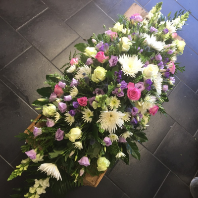 Pink & Lilac Casket Spray - Pink & Mauve Double Ended Casket Spray
A beautiful Pink and Mauve double ended spray. Pink Aqua Roses, Stocks, Freesia White Anastasia Blooms and lilac Eustomia sit perfectly alongside variegated lime Dracaena, Aralia leaves, Cocculus, Salal and Statice.

Hand delivered by your local florist in Bury St edmunds Susettes Flowers.

Image shown is Large 5ft.

Also available in Standard & Medium Sizes.